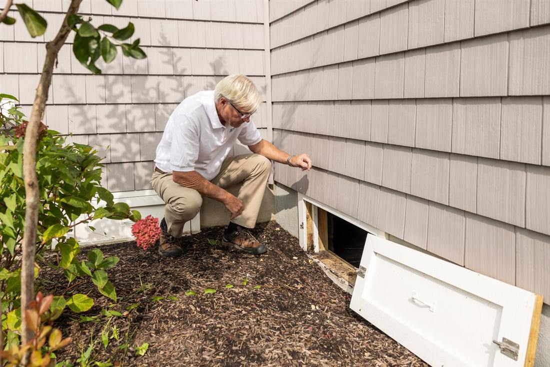 Inspector checking a crawl space vent for moisture and mold outside a Gettysburg PA home