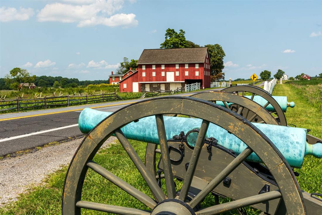 Red barn and cannons on the battlefield in Gettysburg PA, where older buildings face humid summers and damp foundations