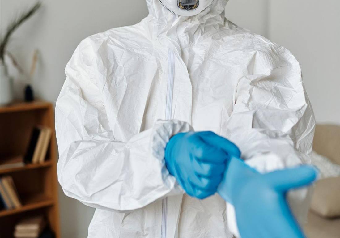 Mold remediation worker in a white protective suit putting on gloves before black mold removal in Gettysburg PA